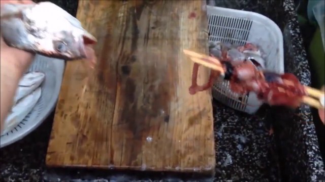 Elle vide un poisson à l'aide de 2 baguettes