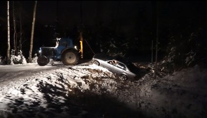 Un tracteur essaye de sortir une Bmw d'un fossé.