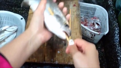 Elle se sert de deux baguettes en bois pour vider le poisson. Sa technique est rapide et soignée !