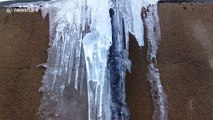 This frozen drainpipe with water flowing down it is strangely beautiful