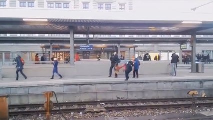 Le chien d'un policier pousse une femme sur une voie ferrée.