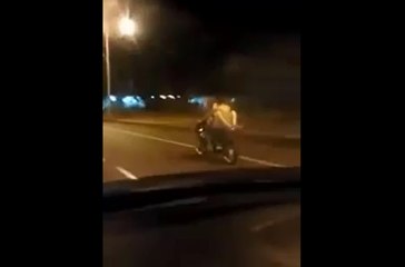 Un couple s'envoie en l'air sur une moto en marche.