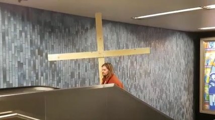 Jésus porte sa croix dans un escalator