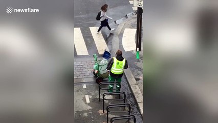 Un employé de la mairie de Paris tente de vider un caniveau repli d'eau à la pelle