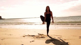 Girl practices yoga near the ocean.