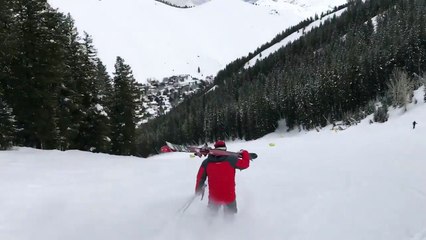 Un skieur descend une piste sur ses bottes avec ses skis sur l’épaule