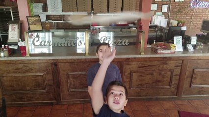 Deux enfants font tourner de la pâte pizza