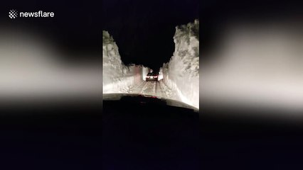 Motorists drive between snow banks after blizzard in Canada