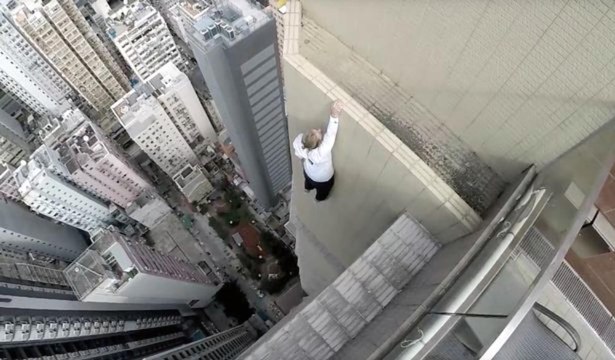 Cet homme joue avec sa vie en faisant des acrobaties du haut d'un gratte-ciel