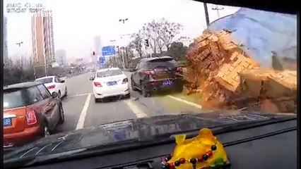 Lorry loaded with bricks flips over burying a car