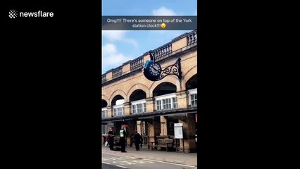Man sits on clock outside York train station