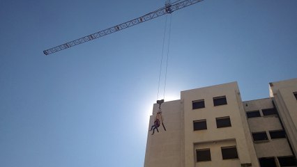 Poor guy getting lifted by a crane atop the building
