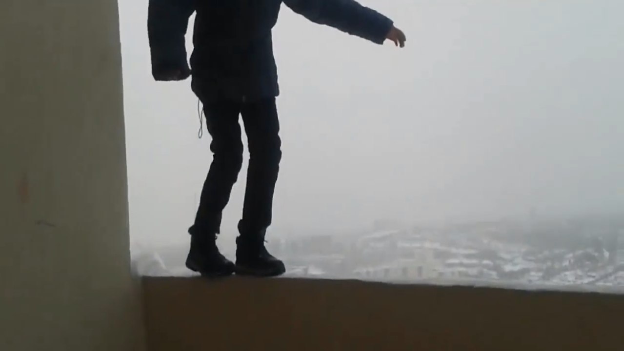 Un enfant marche sur le rebord d'un balcon.