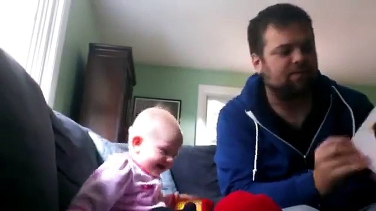 Un bébé rit aux éclats en regardant son oncle interpréter une petite histoire