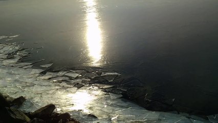Ce lac gelé se brise contre les rochers en bougeant !