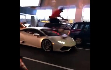 Il roule sur le capot d'une Lamborghini avec son vélo.