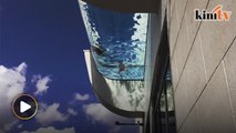 Glass-bottom pool lets people swim in the sky