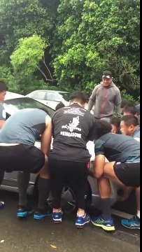 Des rugbymen déplacent une voiture à main-nue