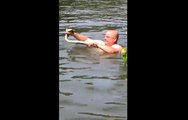 Cet homme tente d'attraper un serpent à mains nues dans l'eau.