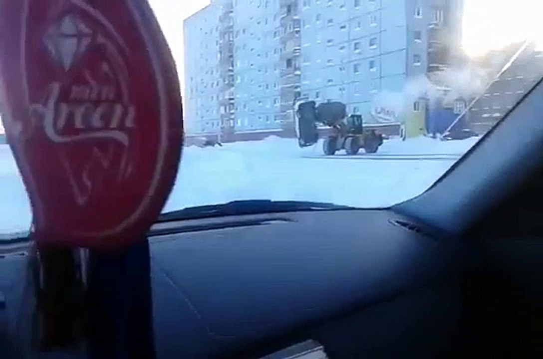 Un homme se sert d'un tractopelle pour déplacer une voiture ventouse.