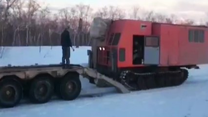Un russe charge un engin de chantier sur son camion