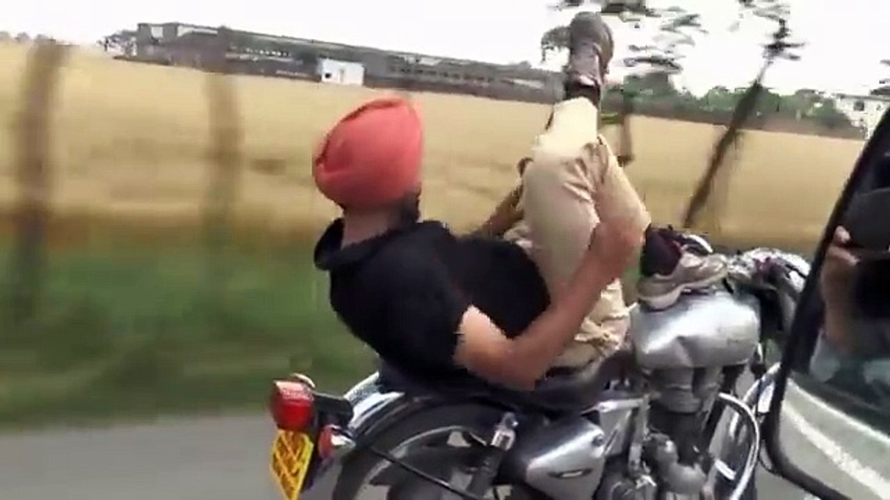 Un homme fait des acrobaties et monte à l'échelle sur sa moto en Inde.