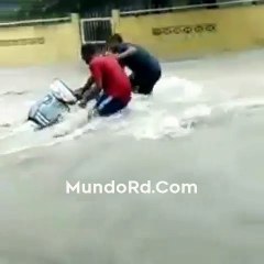 Dos jovenes luchando con la corriente que arrastra su pasola en RD