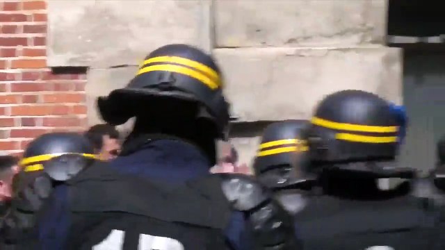 Un CRS frappe avec sa matraque les manifestants qui ne lèvent pas les bras