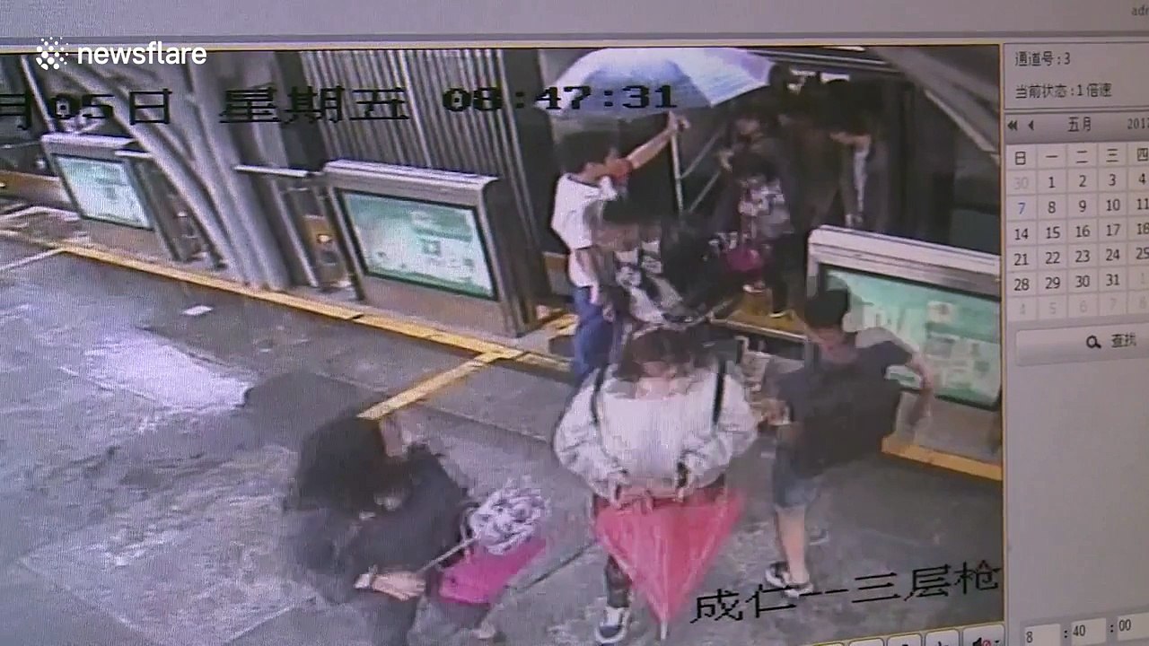 Bus station worker holds umbrella for commuters on rainy day