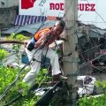 Hombre con una sola mano en un poste de luz poniendo su vida en peligro