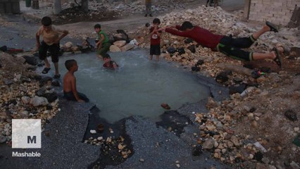 Syrian children use bomb crater as makeshift swimming pool