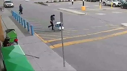 Une femme sort d’un supermarché en courant après avoir volé un caddie plein