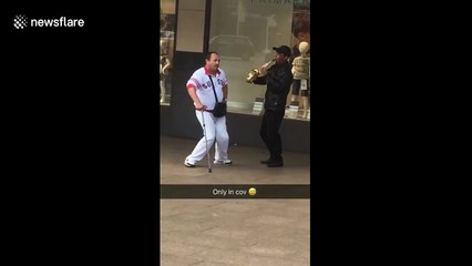 Man with walking stick dances along to street musician