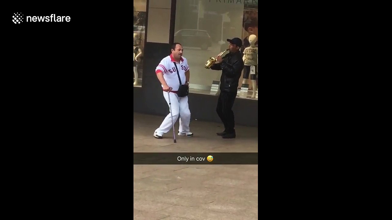 Man with walking stick dances along to street musician