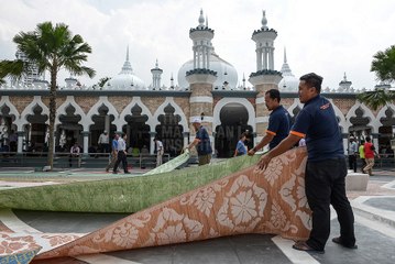 Rolling up prayer mats Masjid Jamek-style