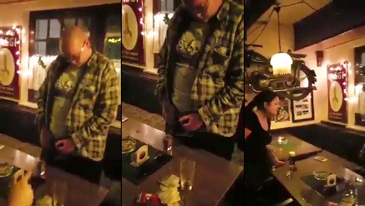 Un homme ivre dans un bar fait pipi dans son verre