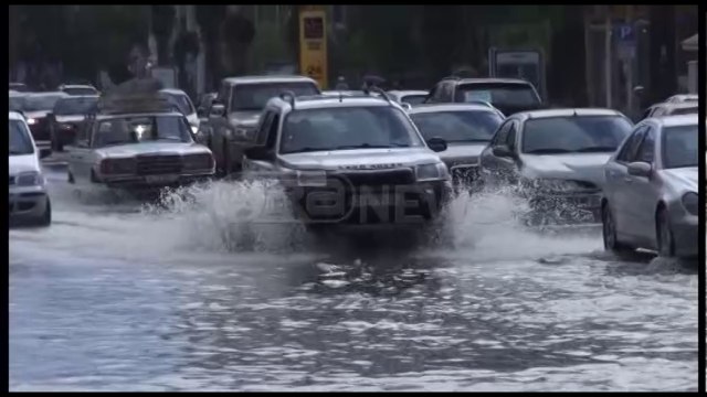 Ora News - Shiu përmbyt rrugët në Vlorë, burri ndihmon të moshuarën të kalojë rrugën