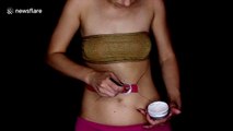 Makeup artist tightens up belt around her stomach in bodypainting illusion
