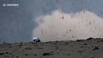 Volcano erupts as man stands next to crater