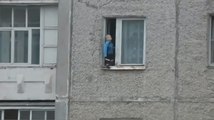 Un enfant s'amuse au bord de la fenêtre du 8ème étage.