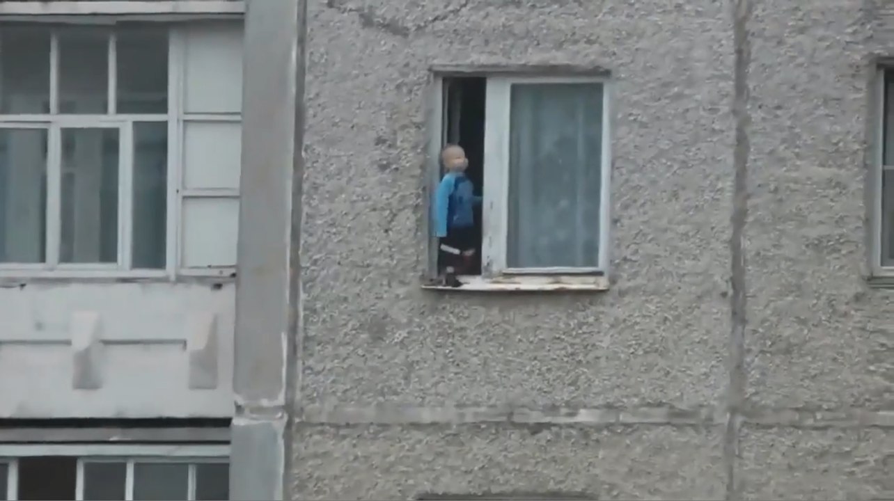 Un enfant s'amuse au bord de la fenêtre du 8ème étage.