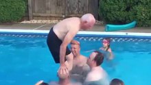 A grandfather makes a backflip in the pool with his grandchildren