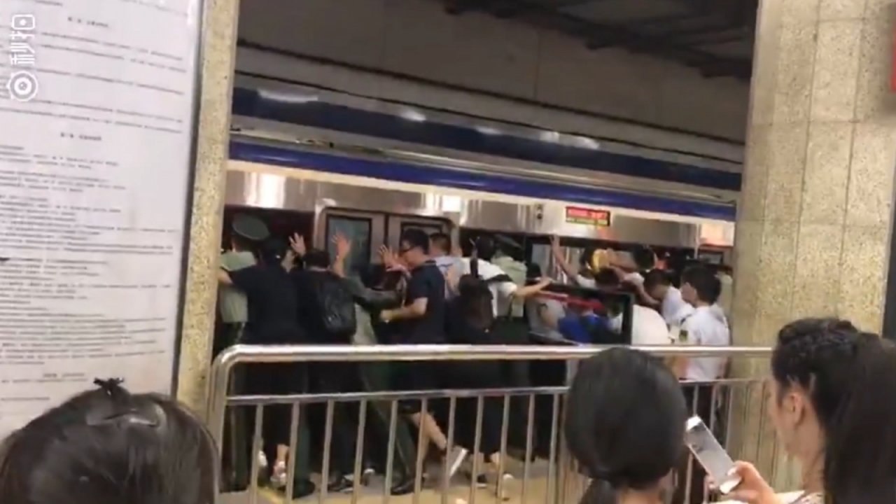 Beijing commuters push train to free man stuck on platform