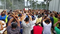 Asylum seekers in Australian offshore detention centre kneel and cross hands in silent protest