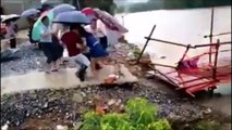 Cette femme traverse un pont sur le point d'etre emporté en pleine inondation