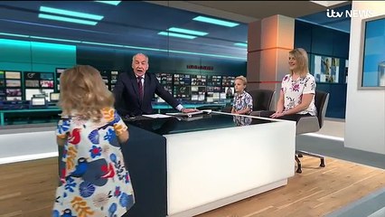 Una niña juega a subir a la mesa de un presentador de tele en directo