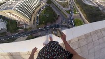Man Skateboards on Edge of Tall Building