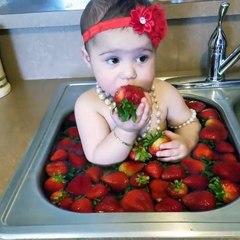 Une toute petite fille prend un savoureux bain de fraises