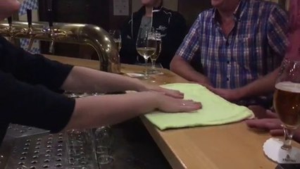 Un homme fait un tour de magie avec une serviette à une serveuse dans un bar