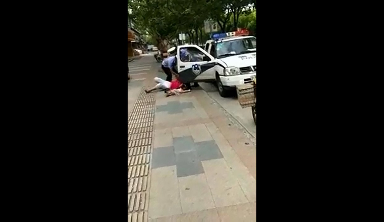 Un policier plaque au sol une femme avec son bébé dans les bras lors d'un contrôle.